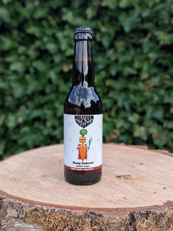 Flaske med Kong Gulerod Amber Lager fra Halstiern Bryghus på en træstub